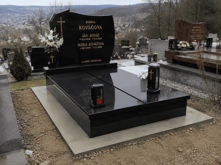 Čierny žulový dvojhrob s nápisom Rodina Kováčová, zdobený kvetmi a lampášmi